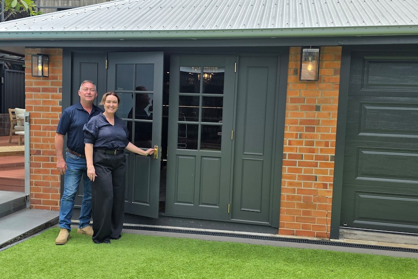 A smiling couple standing in front of a brick building