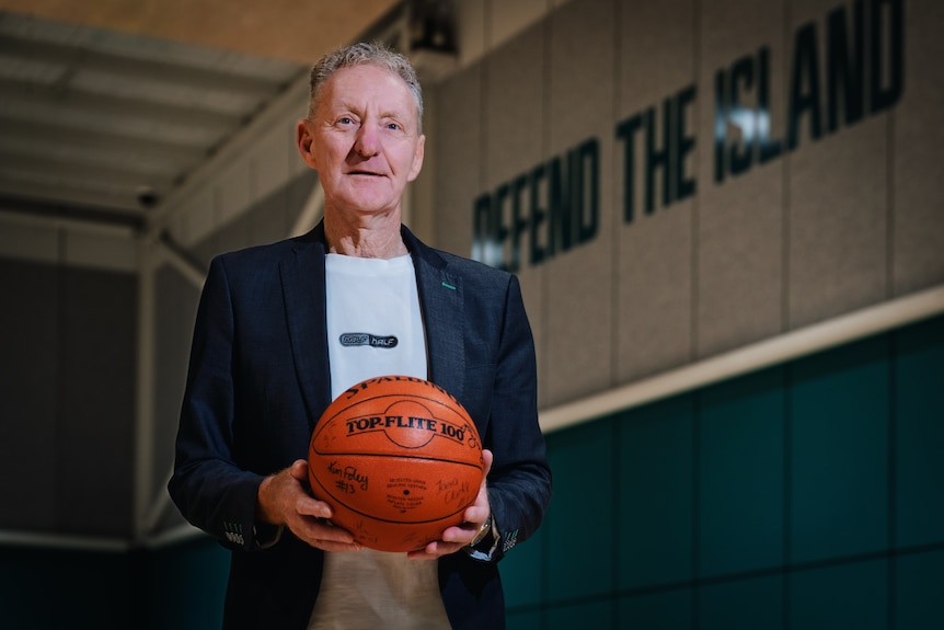 Ross Park, former coach of Tasmania's Islanders women's basketball team, with a basketball. Also in a group photo of team.