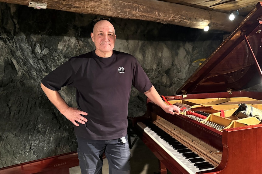 A man stands next to a piano