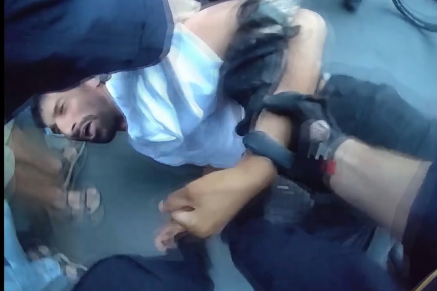 NSW police officers hold a person down on a street in sydney cbd during herzog protest