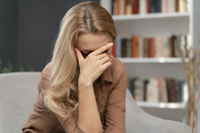 A stressed woman covering her face while sick, showing frustration with doctors.