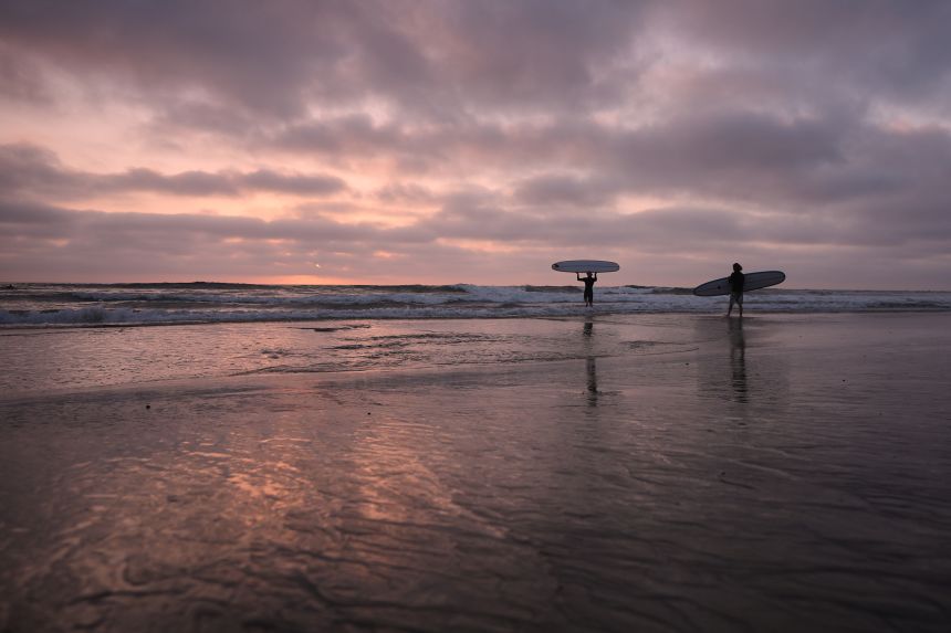 Surfers enter the Pacific Ocean as the sun sets in Encinitas, California, on October 1.