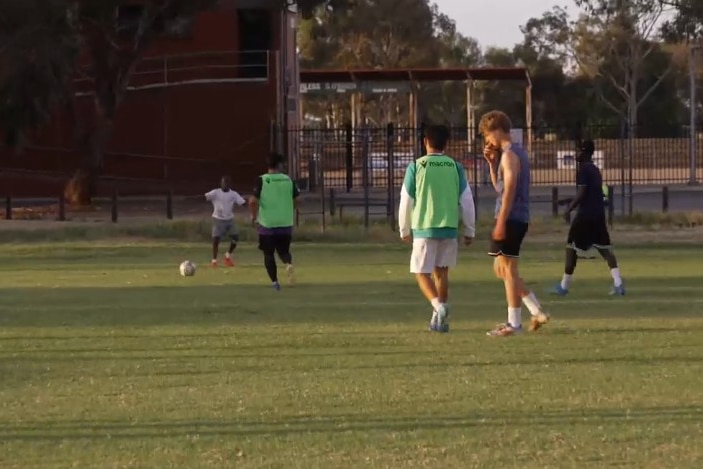 Teenage soccer players on a field at twilight