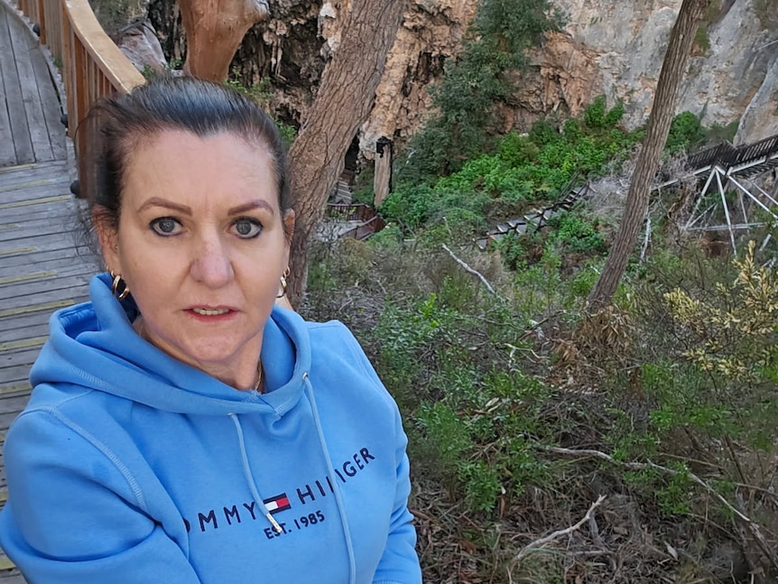 A middle-age woman with dark hair wears a bright blue hoodie. 
