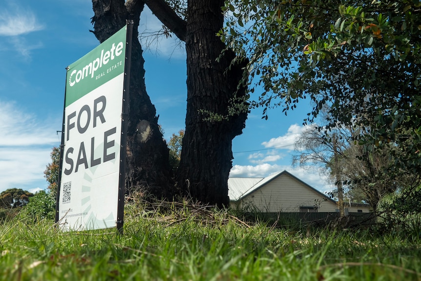 A 'for sale' sign out the front of a grassy regional property. 