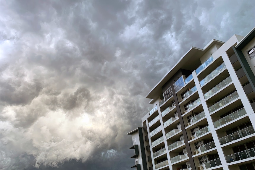 a high rise building with dark storm clouds in the background