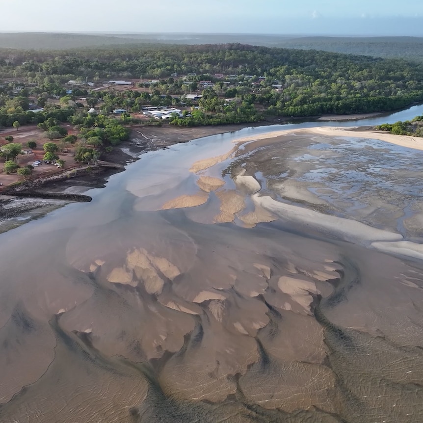 An aerial image of a small community by the water. A creek opens to large sandy flats at low tide.