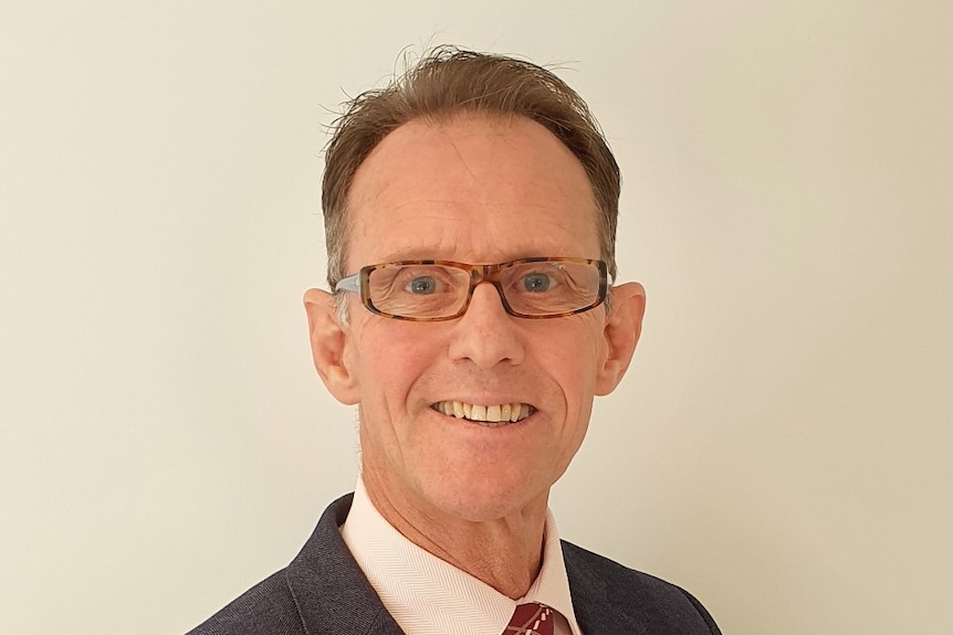 A headshot of a man wearing a suit and glasses