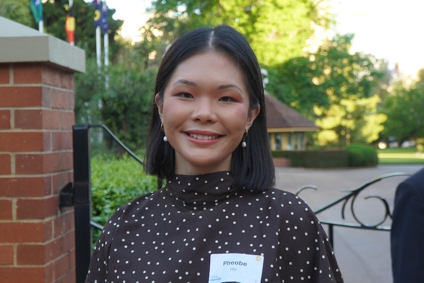 Phoebe Ho stands smiling outside a gate.