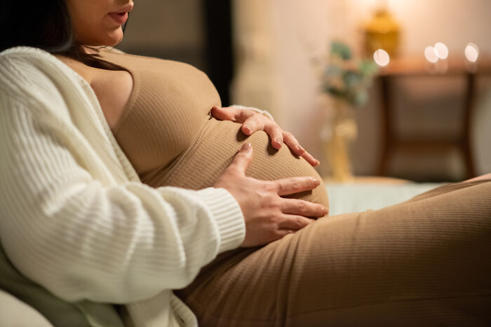 A pregnant woman holding her belly, reflecting the feeling of being sick while expecting.