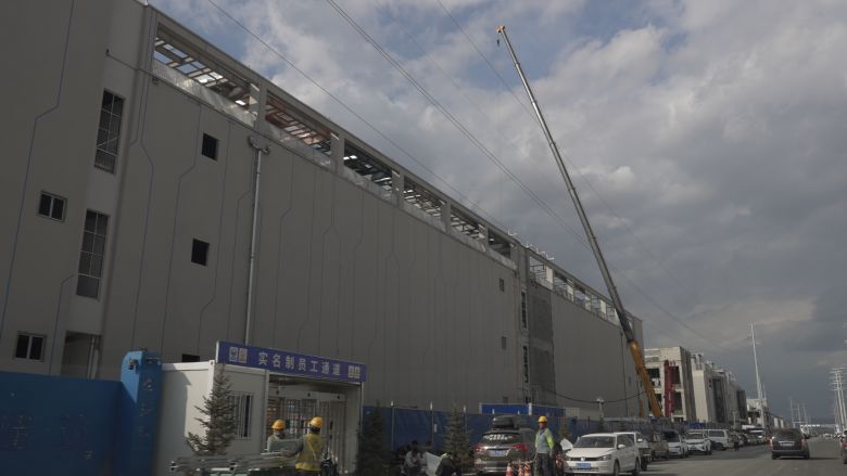 Construction workers are seen outside the gated entrance to a data center being built in Ulanqab's Bayin industrial zone.