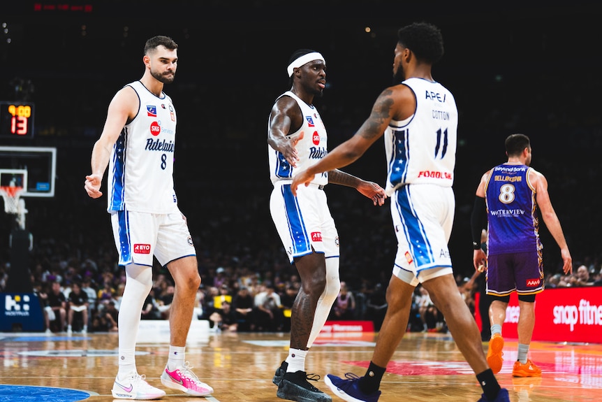 Three Adelaide 36ers players encourage each other during a match