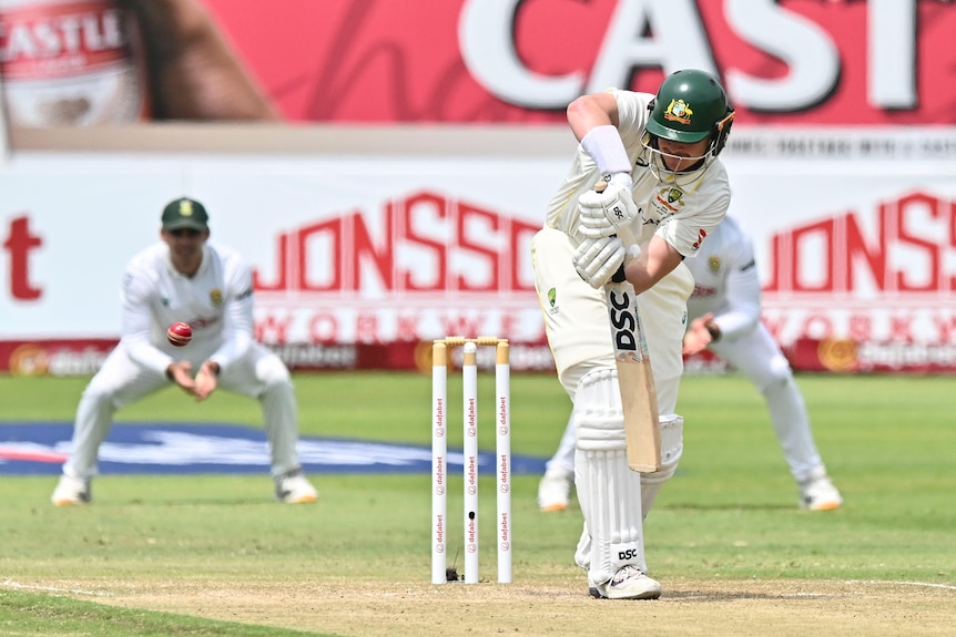 A cricket batter plays an on-side shot with stumps and wicketkeeper behind him