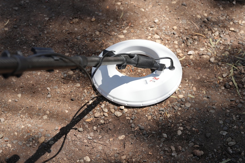 A metal detector scanning dirt.
