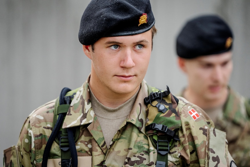 Young man in a military beret with gold broach and green patterned military fatigues