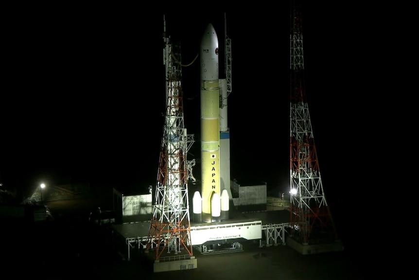 night shot of rocket containing capsule lit up by ground lights prepares for lift off.