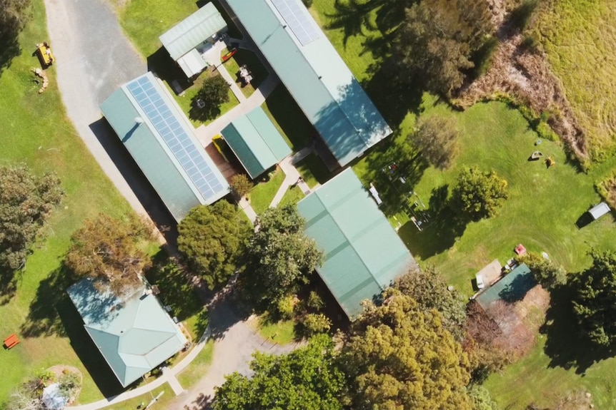 Aerial Photo of a series of a building structures connected by paths surrounded by grass in a rural setting.