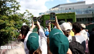 Fans hold up mobile phones outside the show courts at Wimbledon