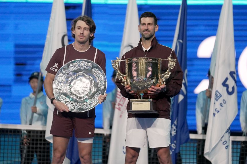 Djokovic poses with the trophy alongside Australia's Alex de Minaur at the China Open on October 6.