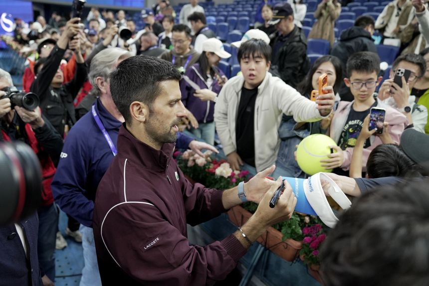 Djokovic signs autographs for fans after winning the men's final on October 6