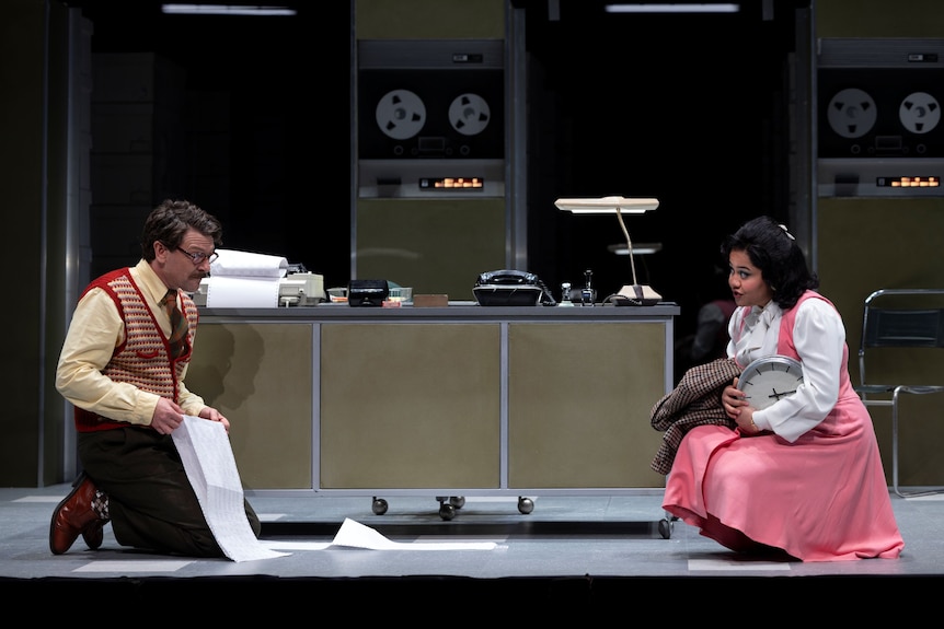 On stage, Dan Spielman, 47, kneels going through pages of code, as Manali Datar, 28, looks at him, clock under her arm.