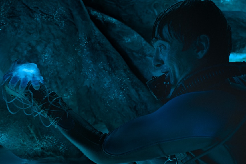 A man holds a blue jellyfish in a whale stomach