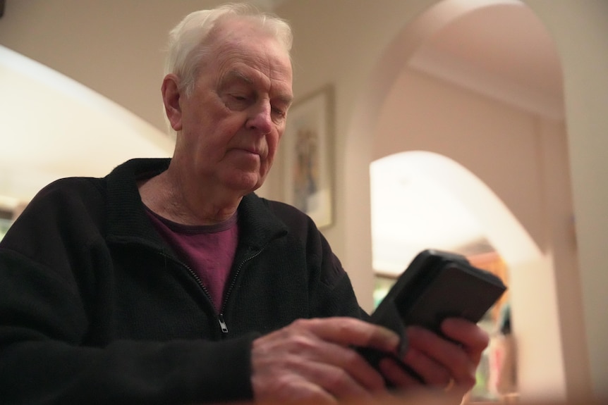 Bob Emery looks at his mobile phone
