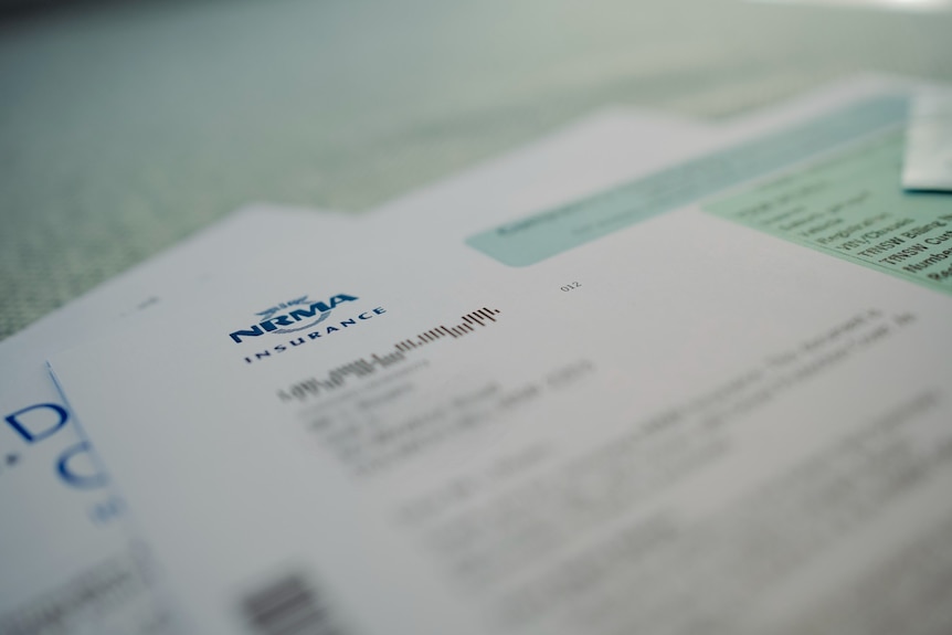 An up close photo of NRMA Insurance paperwork with the name logo in blue, and key private details blurred.