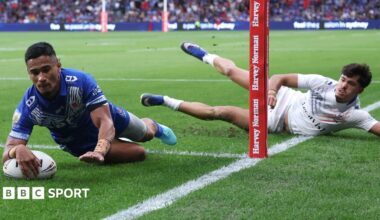 Sua Fa'alogo dives to score a try as a France defender lies on the ground watching him