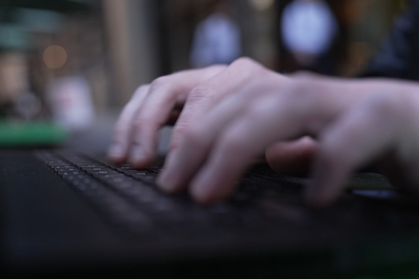 A close up of a pair of hands typing on a laptop keyboard