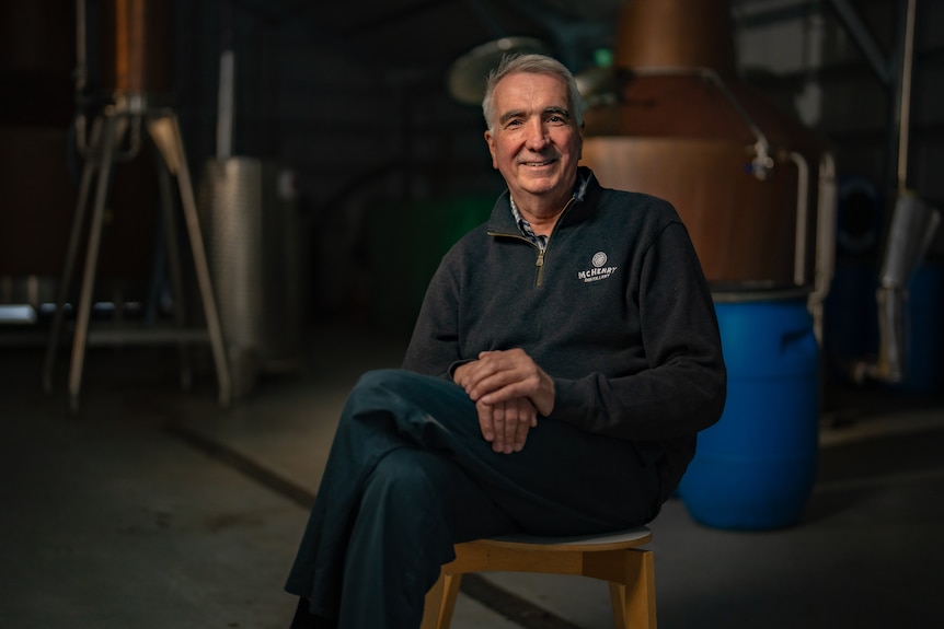 A man sits in a dark distillery