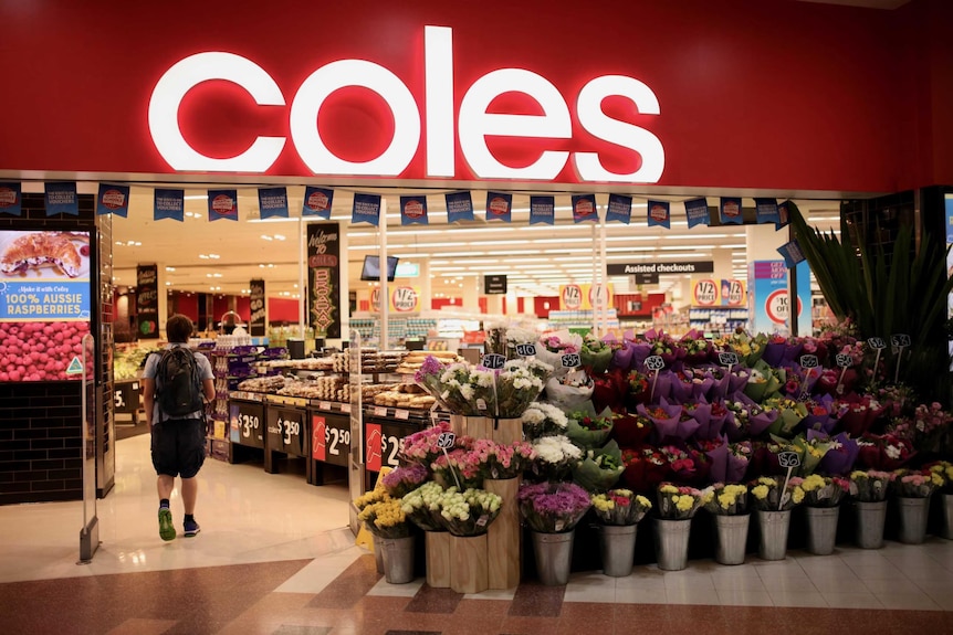 A Coles shopfront with buckets of flowers.