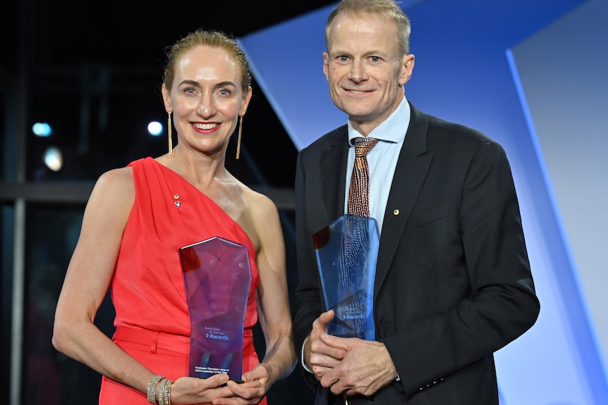 A woman and a man dressed formally with awards.