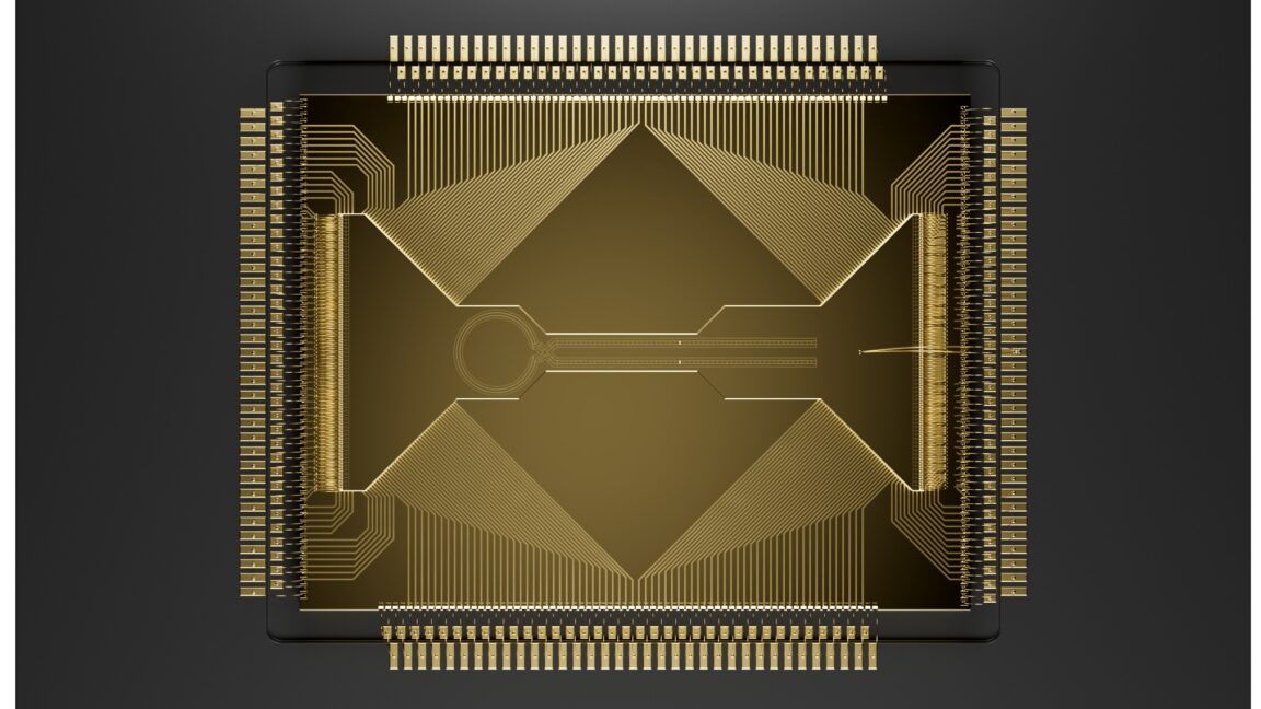 Image of a grey square with lots of wires heading into a gold chip with a complicated arrangement of channels on its surface.