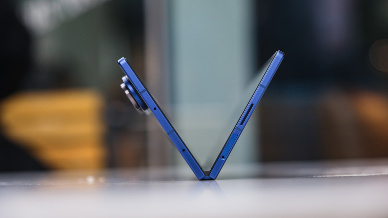 Blue foldable smartphone partially open in a V shape on a table.