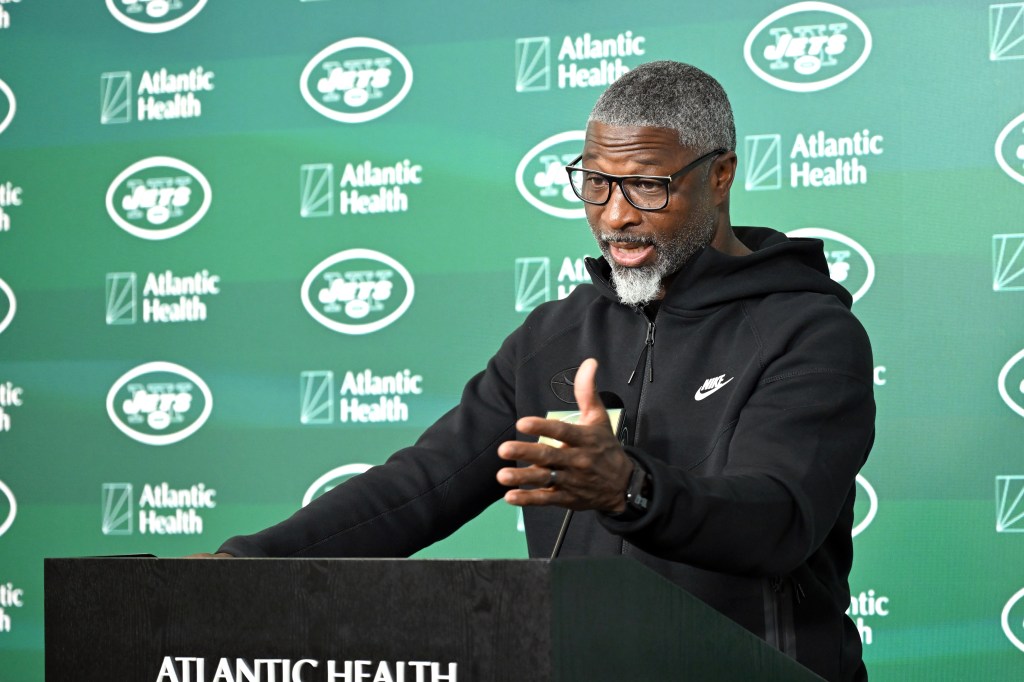Jets head coach Aaron Glenn speaks to the media at a podium.