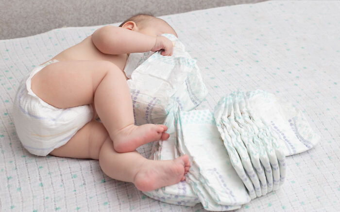 A baby lying on a bed surrounded by diapers, representing a medical story about pediatric care.