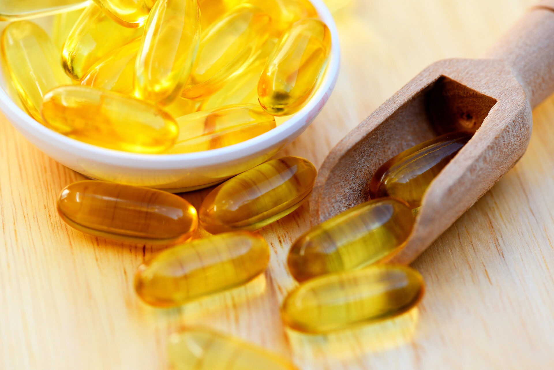 Cod liver oil omega 3 gel capsules, Fish oil capsules with omega 3 and vitamin D in scoop on wooden background healthy diet concept