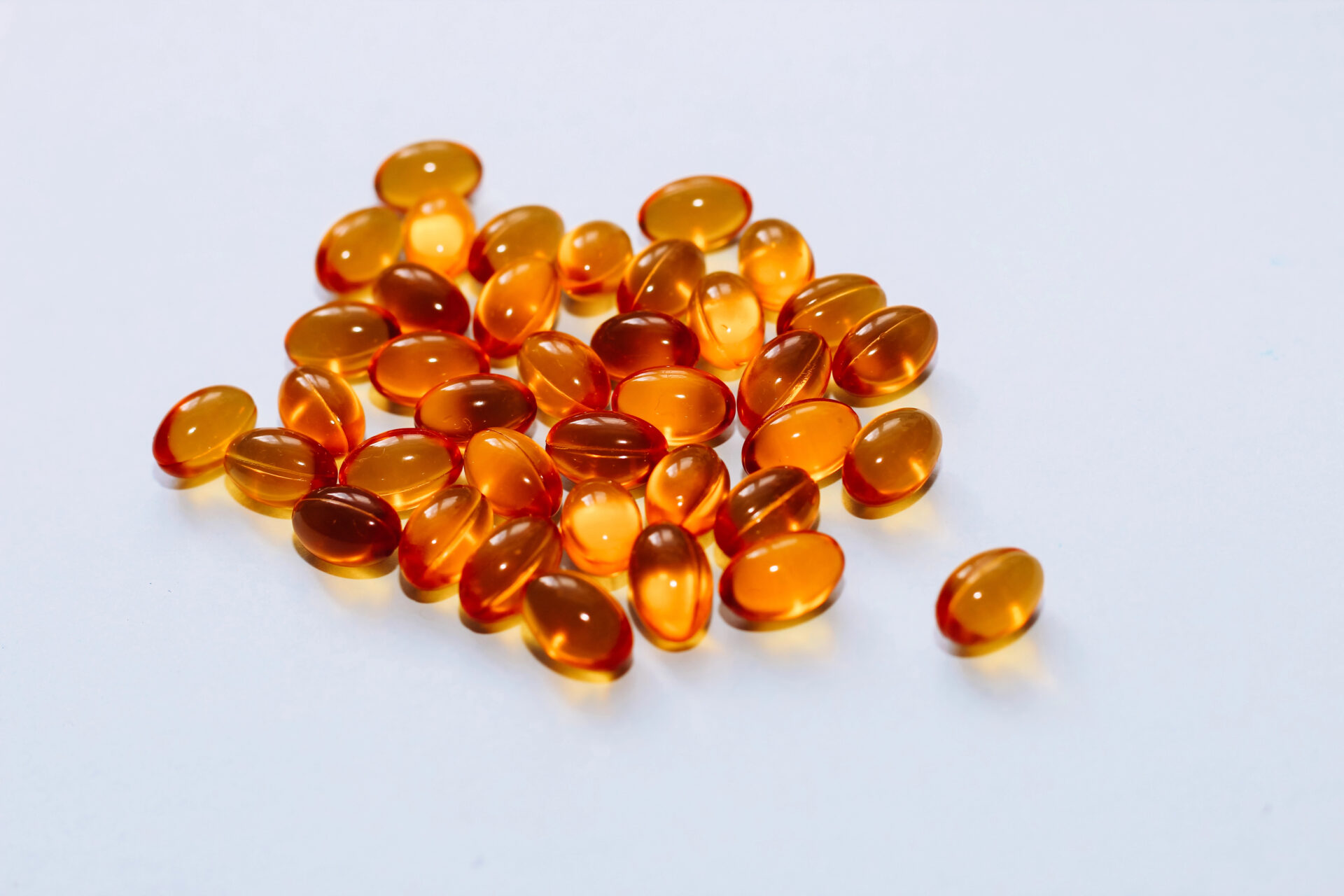 Fish oil pills in a golden jelly shell on a white background.