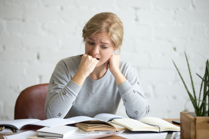 An anxious young woman biting her nails while studying, illustrating mental health problems in Gen Z.