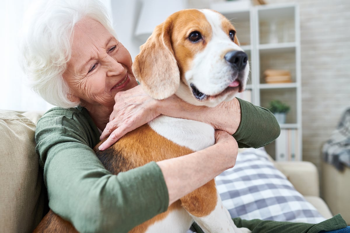 Smiling person holding a dog.