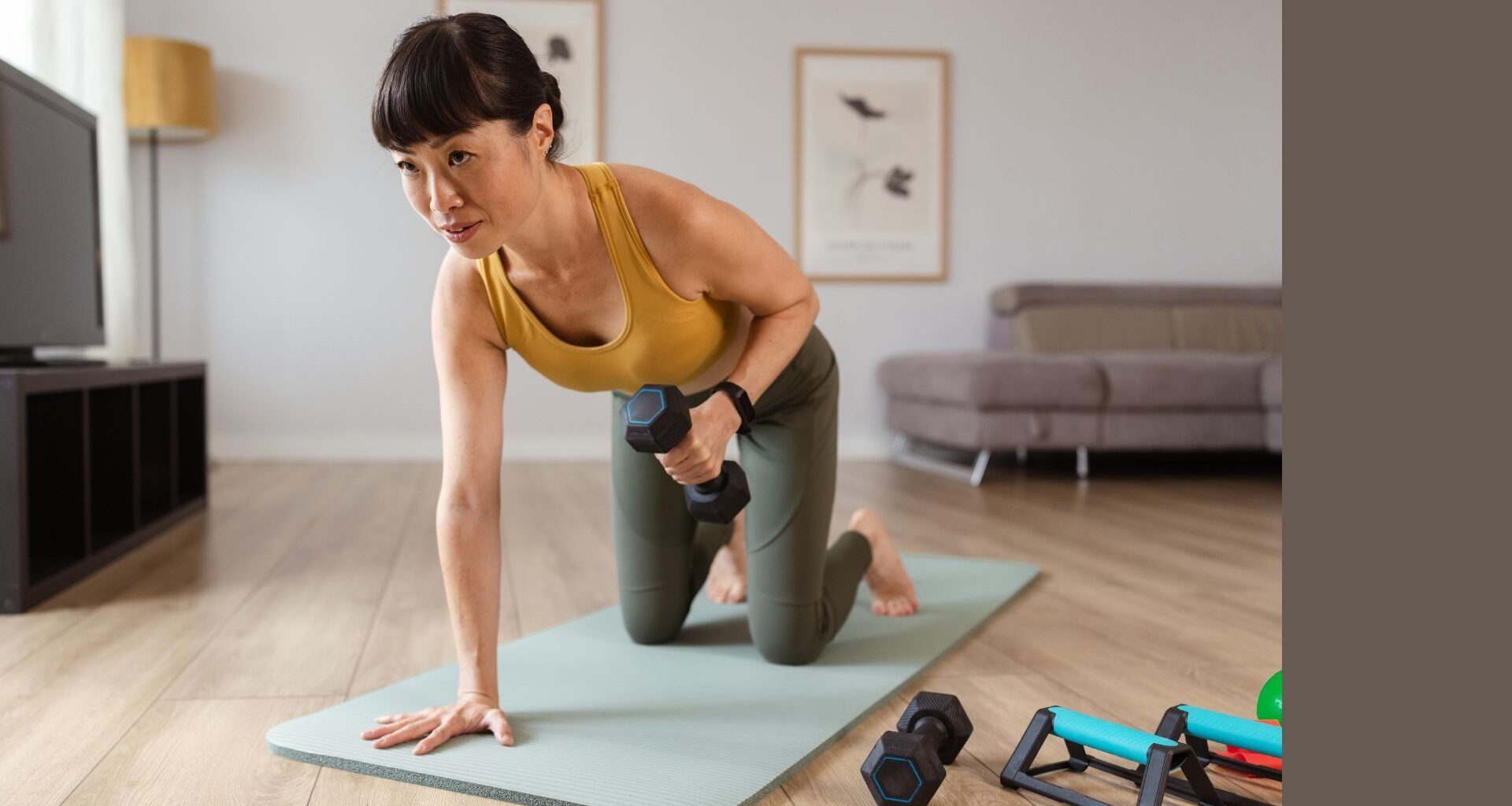 Woman lifting dumbbells on yoga mat