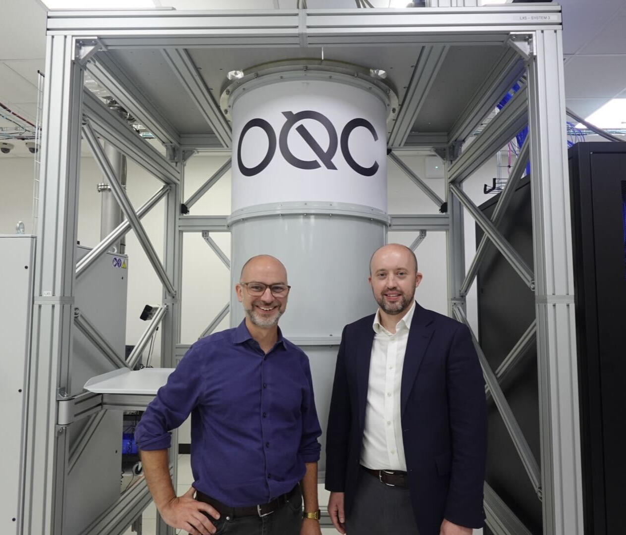 Two men standing in front of an OQC quantum computer.