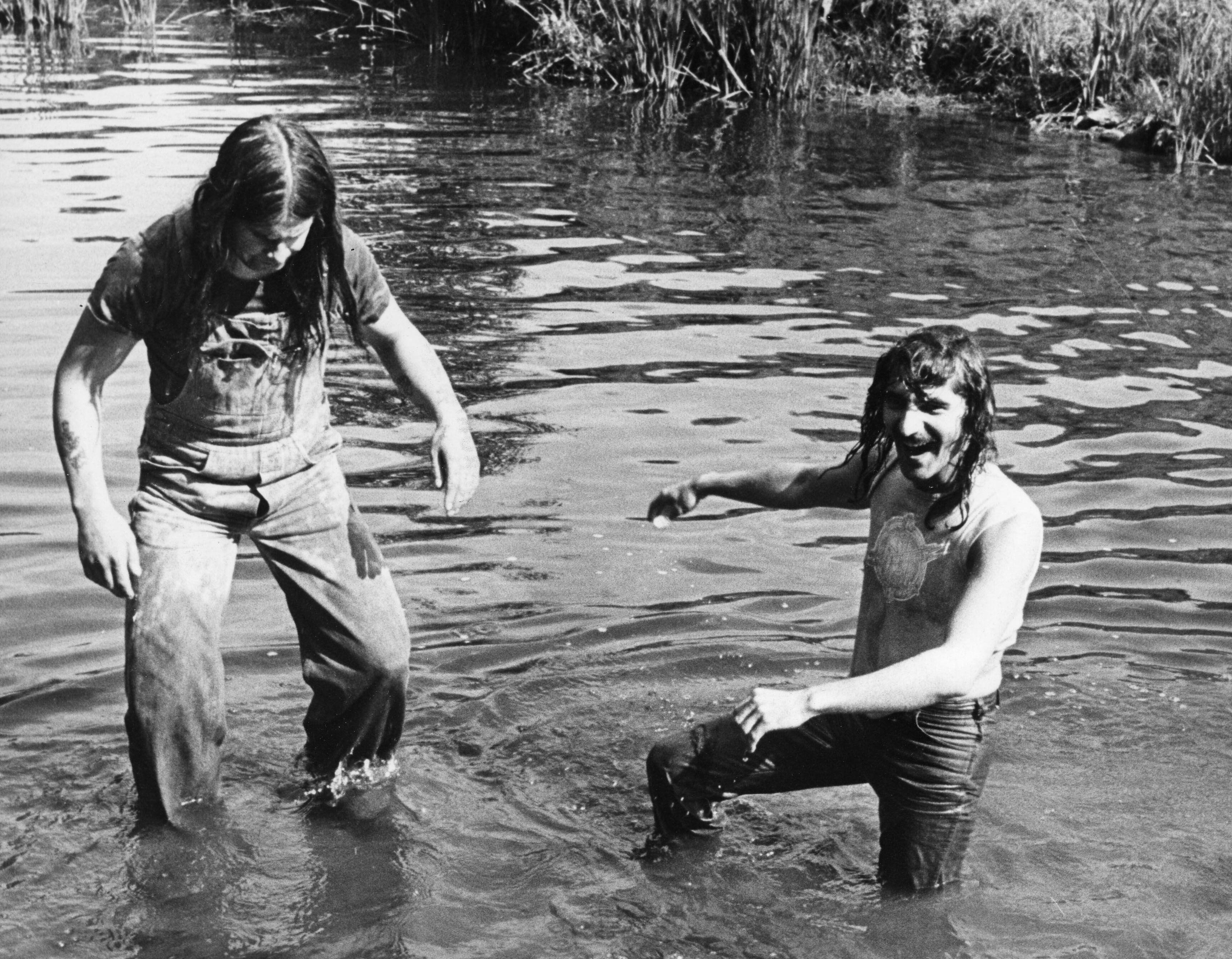 Ozzy Osbourne and Geezer Butler of Black Sabbath wading in a river.