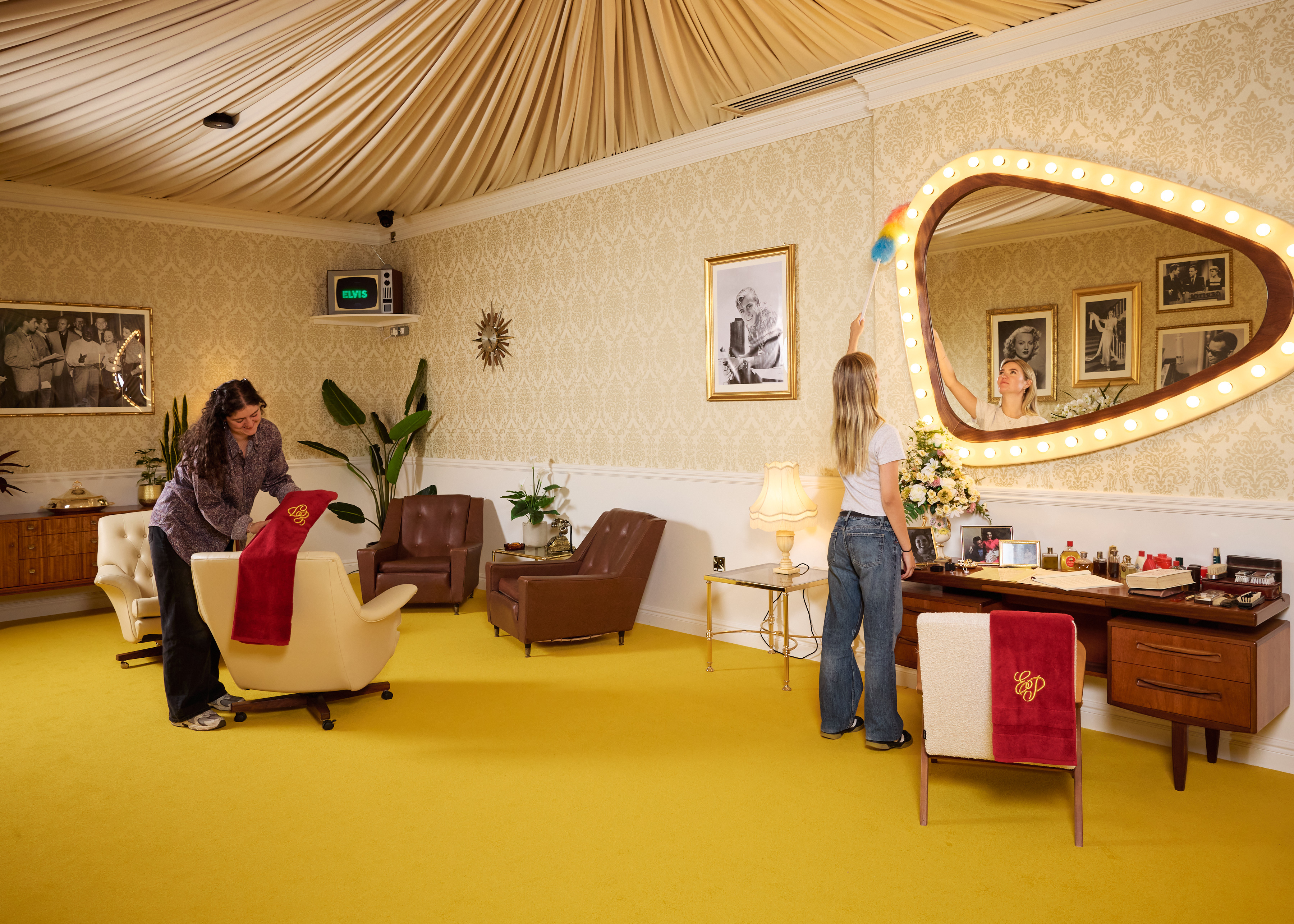 Two people putting the finishing touches on the set of an immersive Elvis experience.