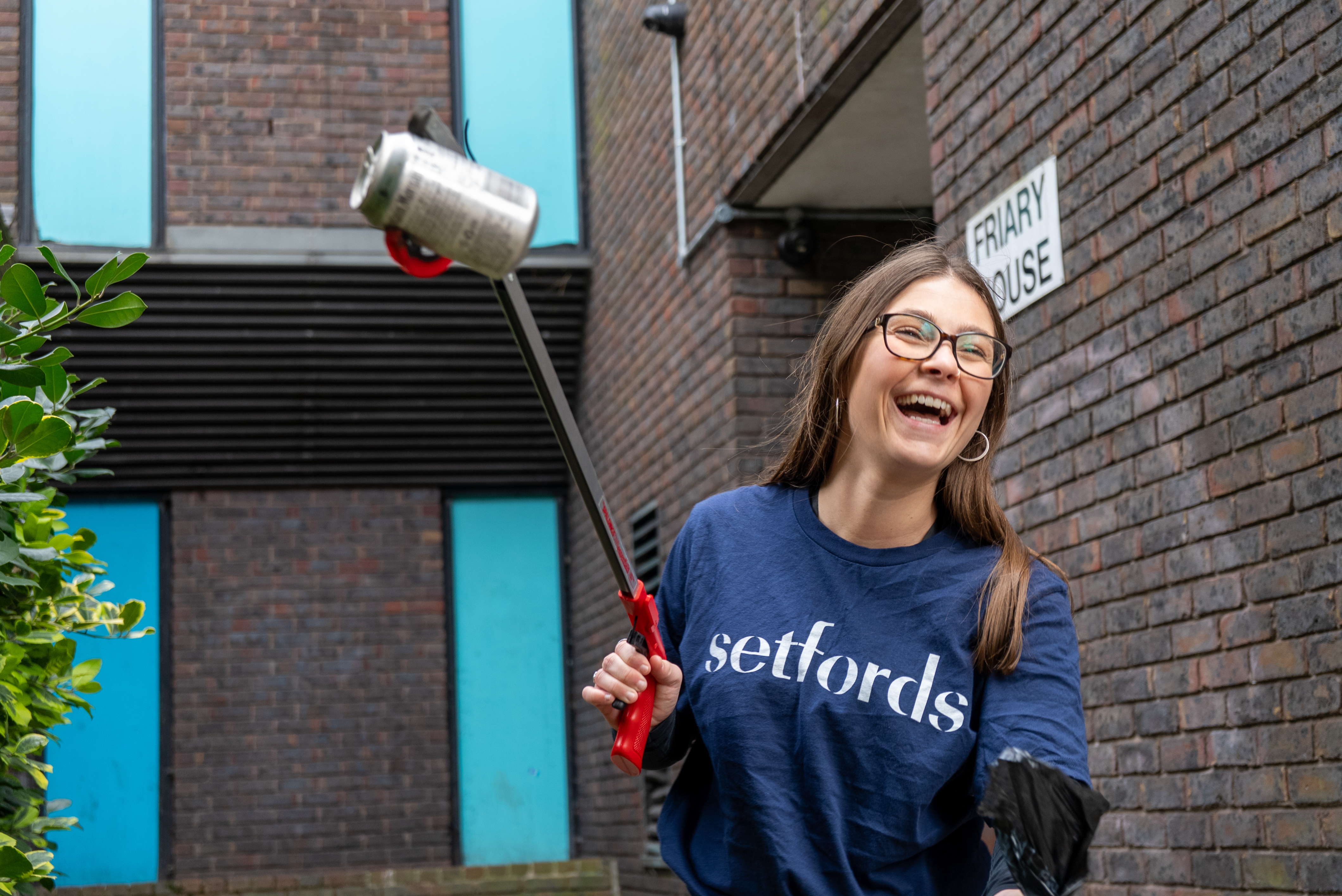 Woman using grabber to pick up trash during a cleanup event.