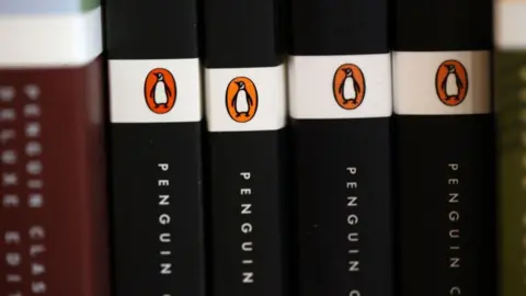 Getty Images The spines of several books, standing vertically. Each is black and the word "Penguin" can be read. They each have the black, white and orange Penguin logo.
