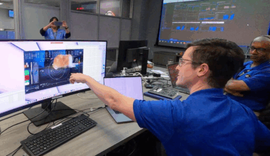 A man sitting at a desk points to a computer monitor that shows a test video of a cat.
