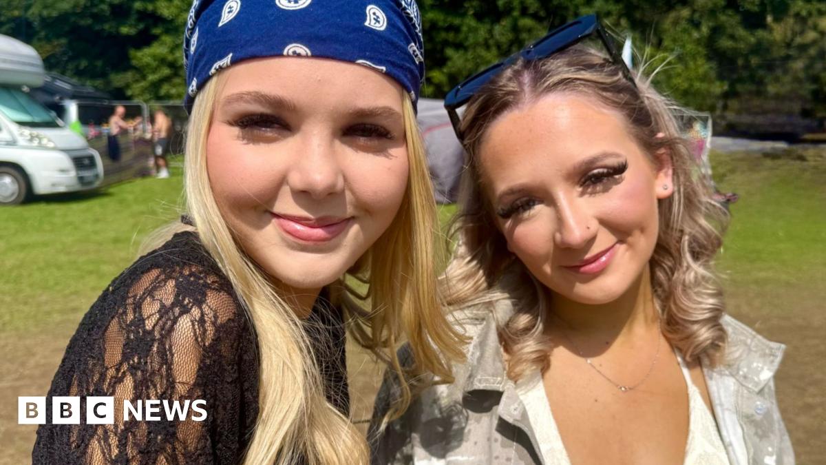 Abi has long brown hair and looks into the camera with a serious expression