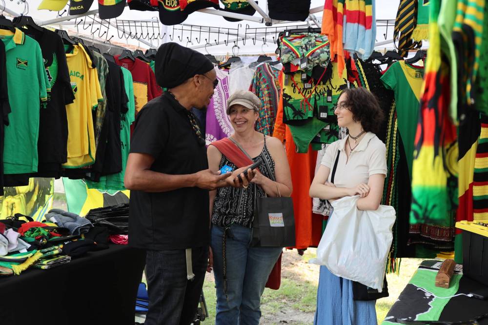 Warren Benns (left), owner of Natural Mystic shares a laugh with Stacey (middle) and Izzy Eaton at the Naija Market in Princess Park Saturday afternoon in downtown Brandon. (Michele McDougall/The Brandon Sun)
